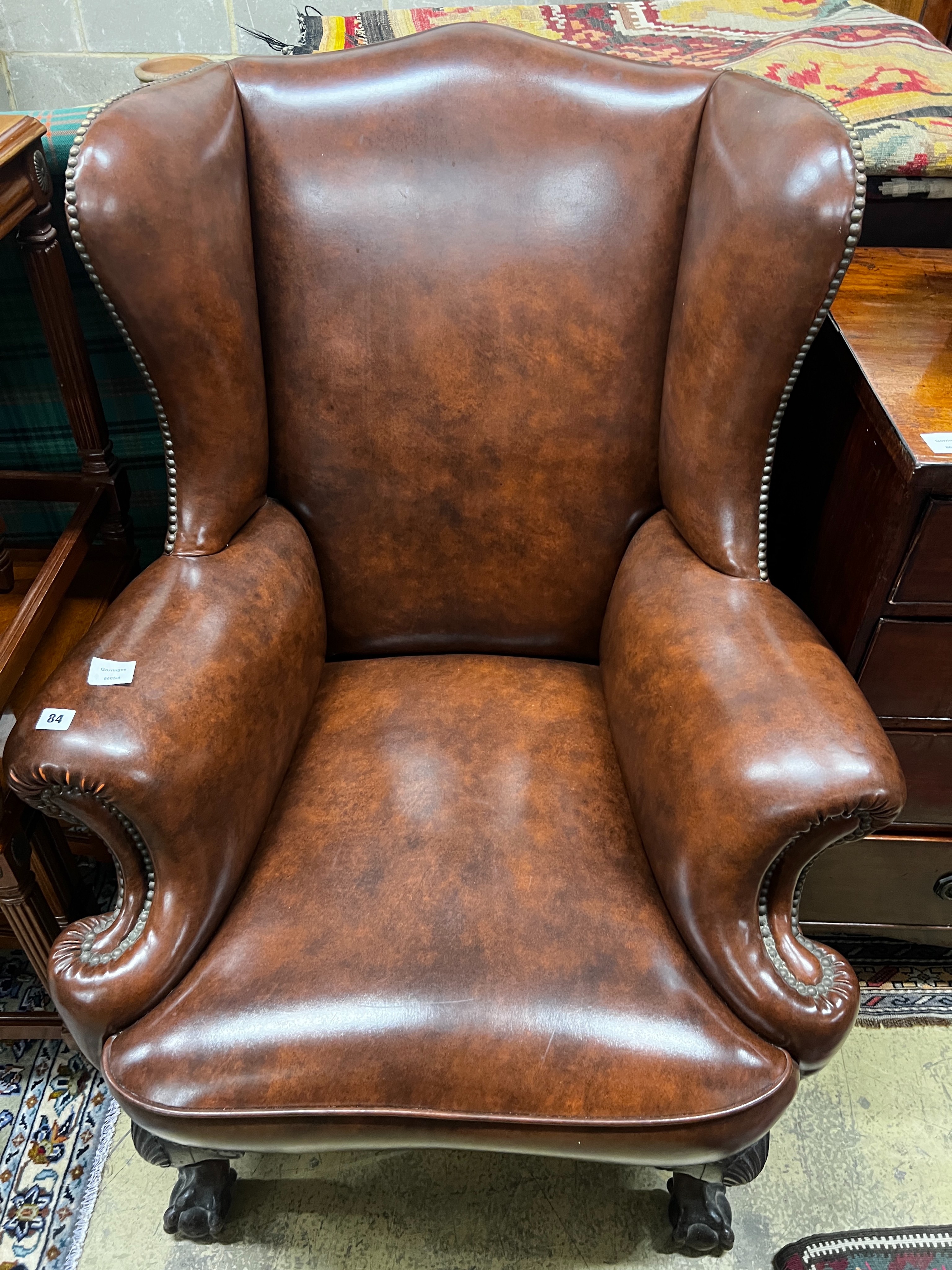 A George II style studded brown leather wing armchair, width 84cm, depth 86cm, height 108cm